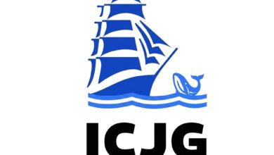 Logótipo do Iate Clube Jardim Guanabara com ilustração de um veleiro, estrelas e uma baleia sobre ondas em tom azul, com a sigla ICJG em destaque
